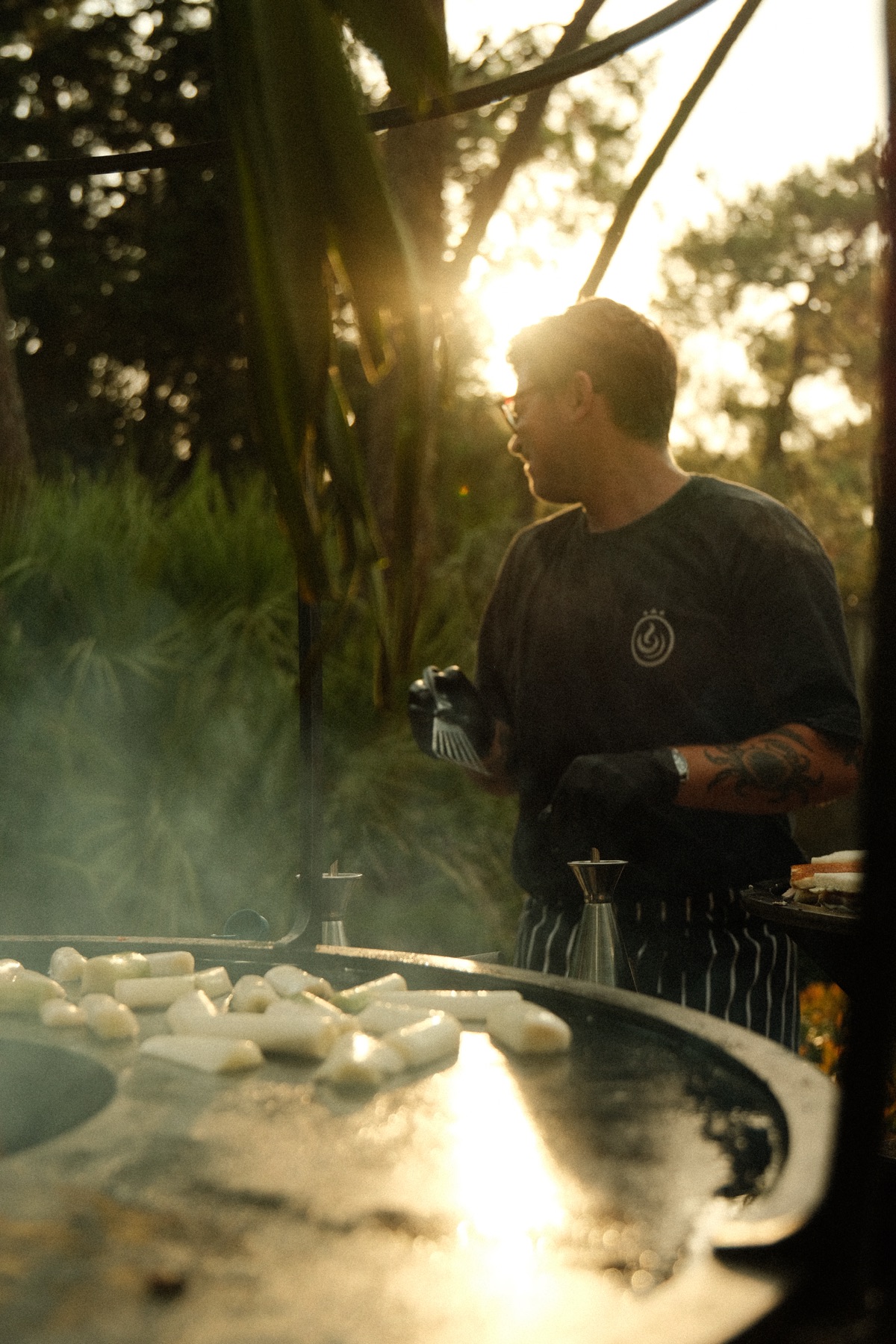 Le chef Maison Gomary au brasero, à contre-jour au coucher de soleil